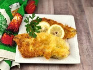 FODMAP foods - Gluten Free "fried" fish with lemon and parsley on a white plate