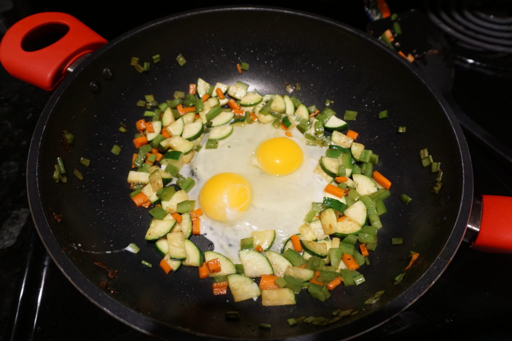 Eggs and vegetables being stir fried. 