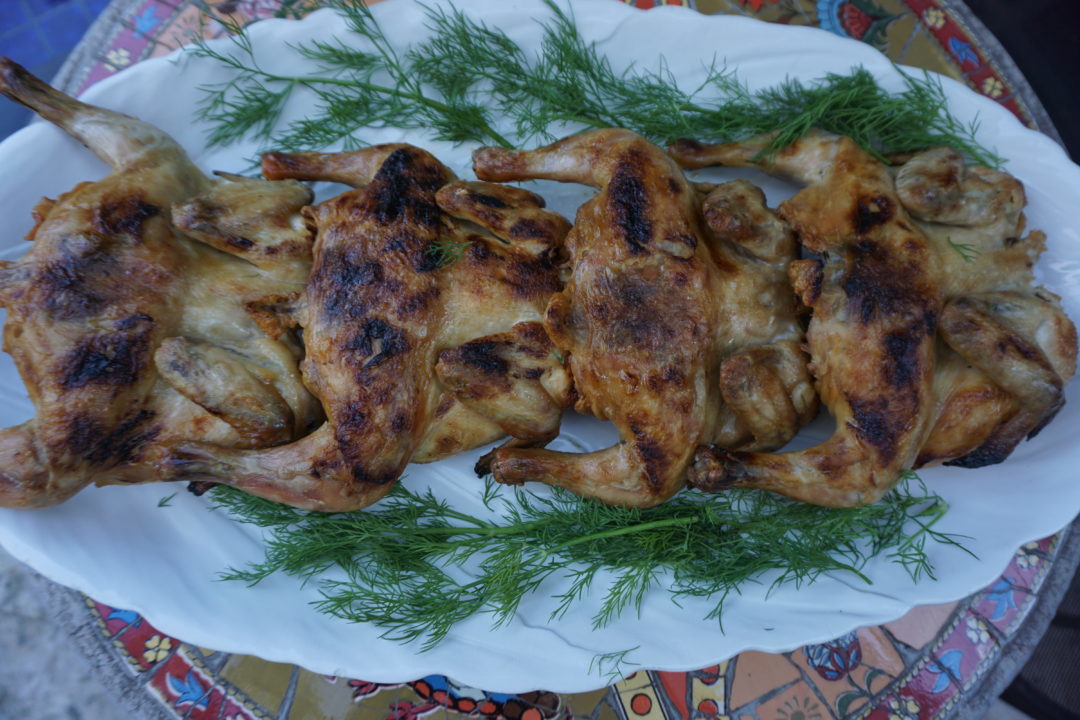 Cooked Cornish Hens on a white platter with dill