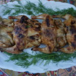 Cooked Cornish Hens on a white platter with dill