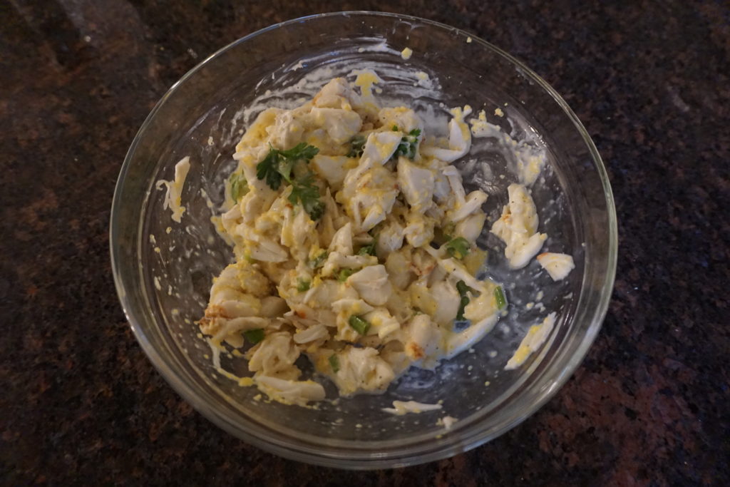 Crab mixture being mixed together in a glass bowl.