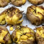 Smashed Potatoes topped with salt, rosemary and olive oil on a parchment lined baking sheet. - FODMAP smashed dish