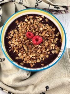 FODMAP safe breakfast - Acai bowl topped with FODMAP safe granola and raspberries