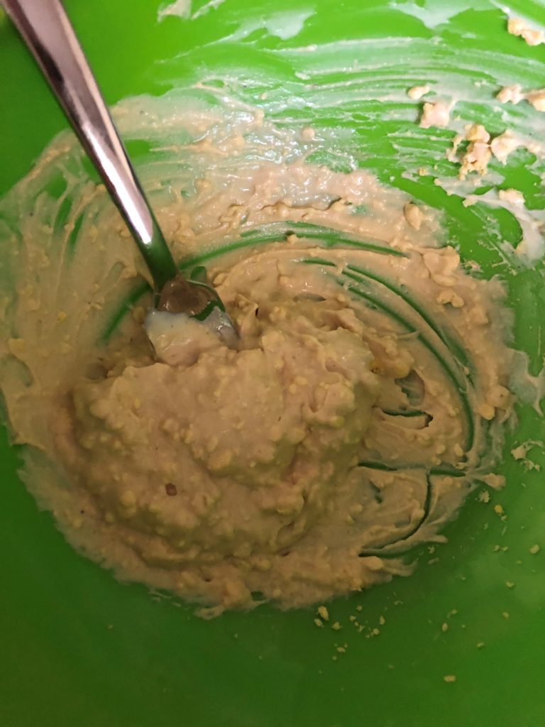 Egg yolk mixed with mayonnaise, mustard, salt & pepper in a green bowl. 