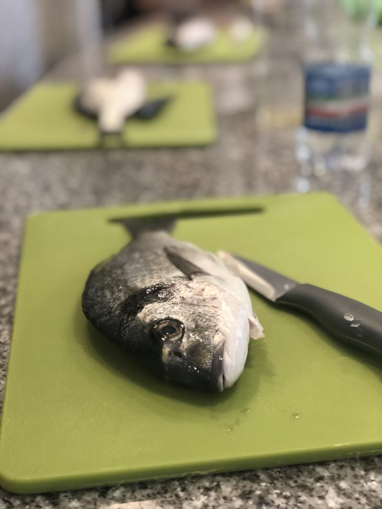 A whole sea bass on a green cutting board, ready to be filleted. 