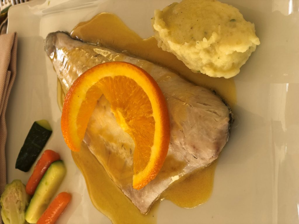 A white plate of sea bass with orange sauce at Locanda La Tirlindana in Lake Como, Italy.