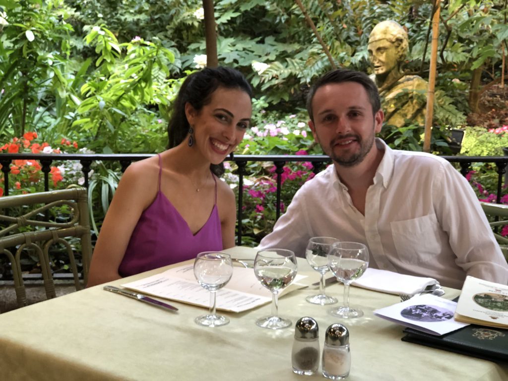 Eugene and I at a table surrounded by flowers and trees in Sorrento, Italy.