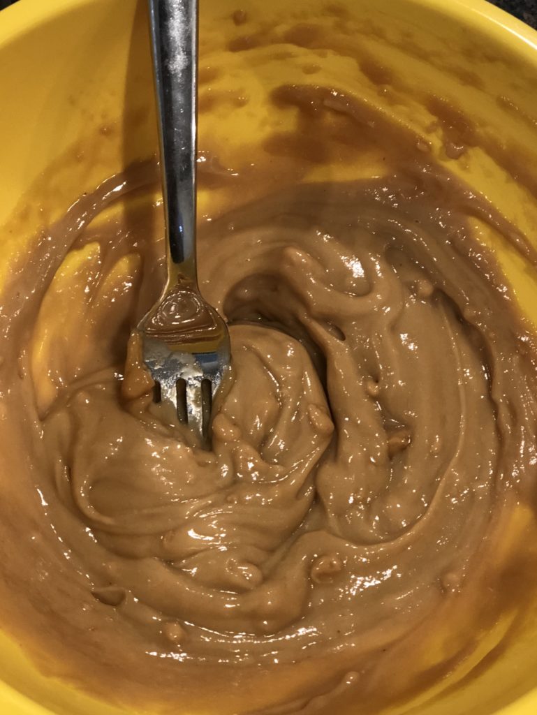 Mixing ingredients for the FODMAP safe peanut sauce in a yellow bowl.